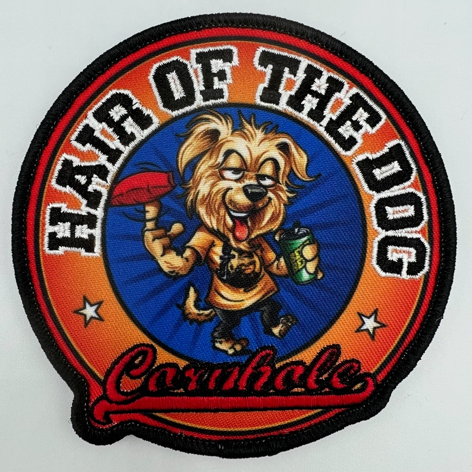 Circular embroidered patch with cartoon dog, Hair of the Dog and Cornhole lettering, and cornhole beanbag.