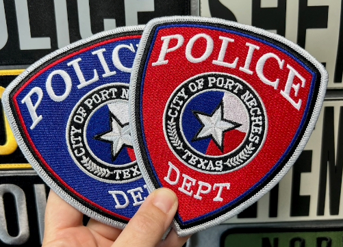 Hands holding blue and red shield-shaped Port Neches Texas Police Department embroidered patches with Texas star seal.